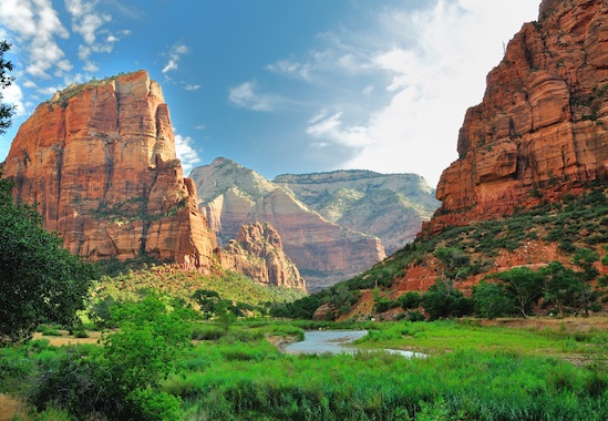 red canyon with green river bank under blue sky